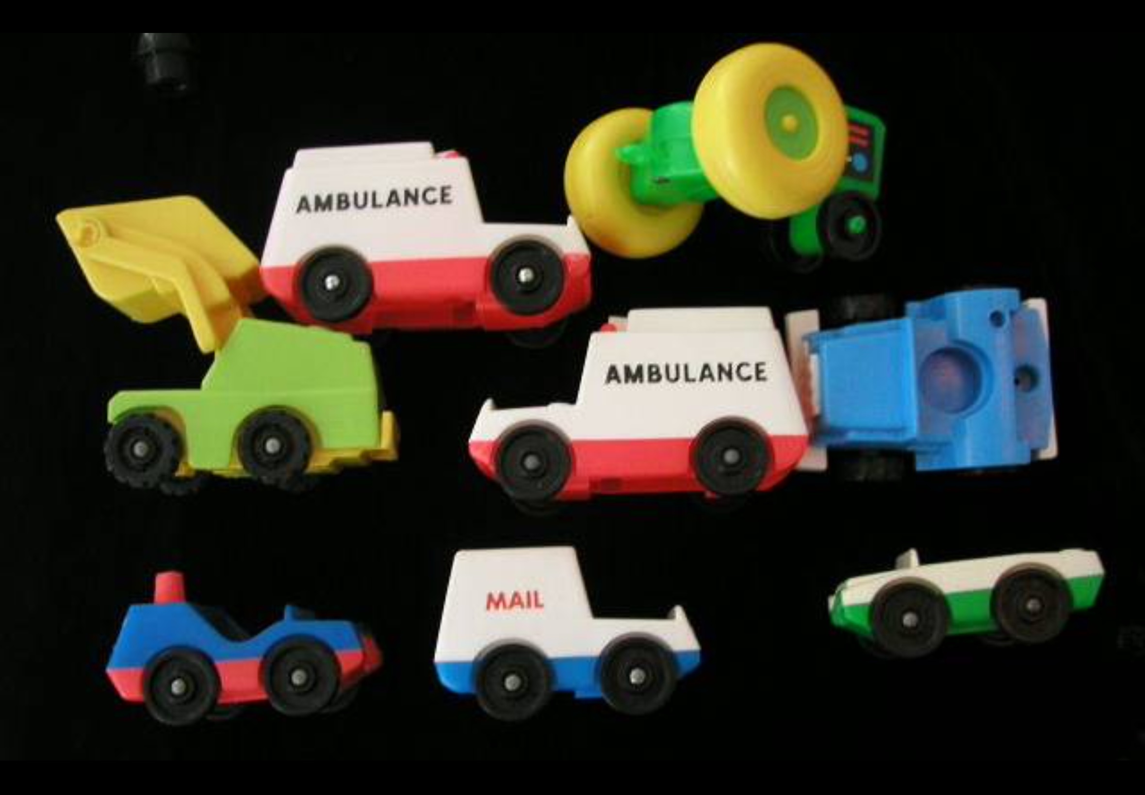 Nine colorful vintage mini toy vehicles arranged on a dark background